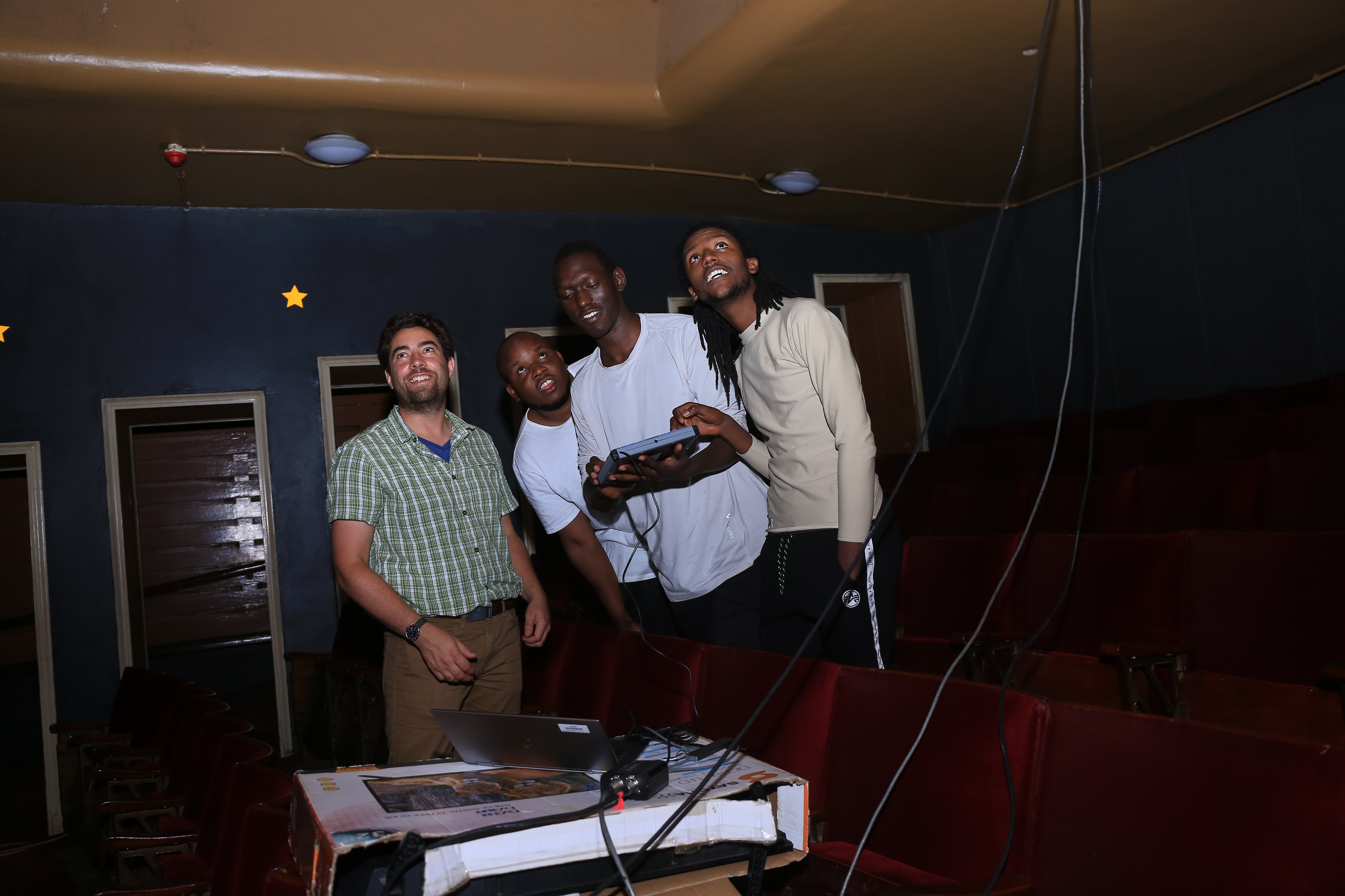 Four people stand in what appears to be a booth and one person is holding a controller. They are all looking up and smiling.