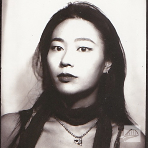 Qiuyi Li headshot. Qiuyi is wearing a black tank top with a silver chain necklace and pendant around her neck. She also has a thin black scarf wrapped around her neck. She has long black hair. The photo is in black and white.