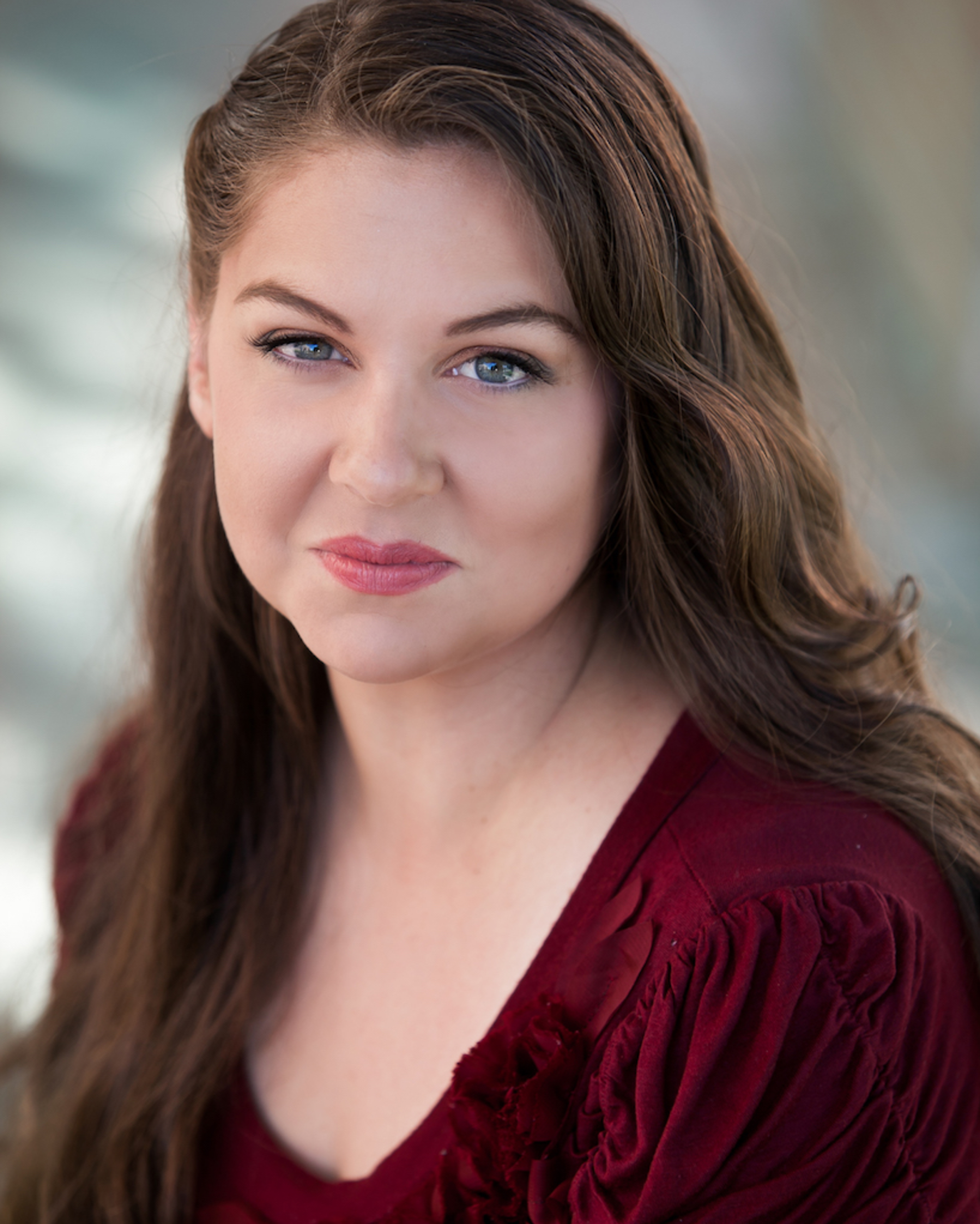 Milinda Weeks headshot. Milinda is wearing a burgundy long sleeve shirt. She has brown hair and is smiling at the camera. The background is a light gray.