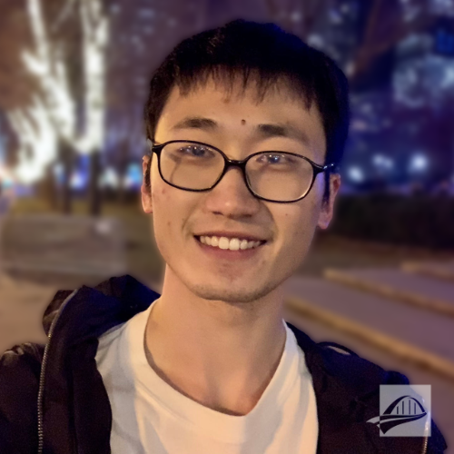 Tom Zhang headshot. Tom is wearing a white t short with a black zip up hoodie over it. He has short black hair and is wearing glasses. He is standing outside in a city at night.